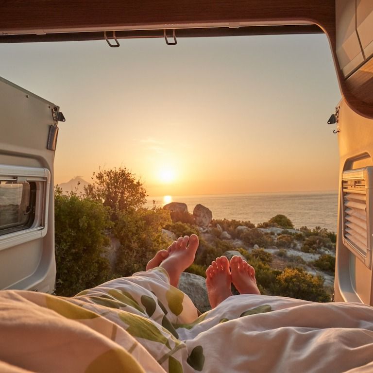 Campervan med par som tittar ut över havet och solnedgången